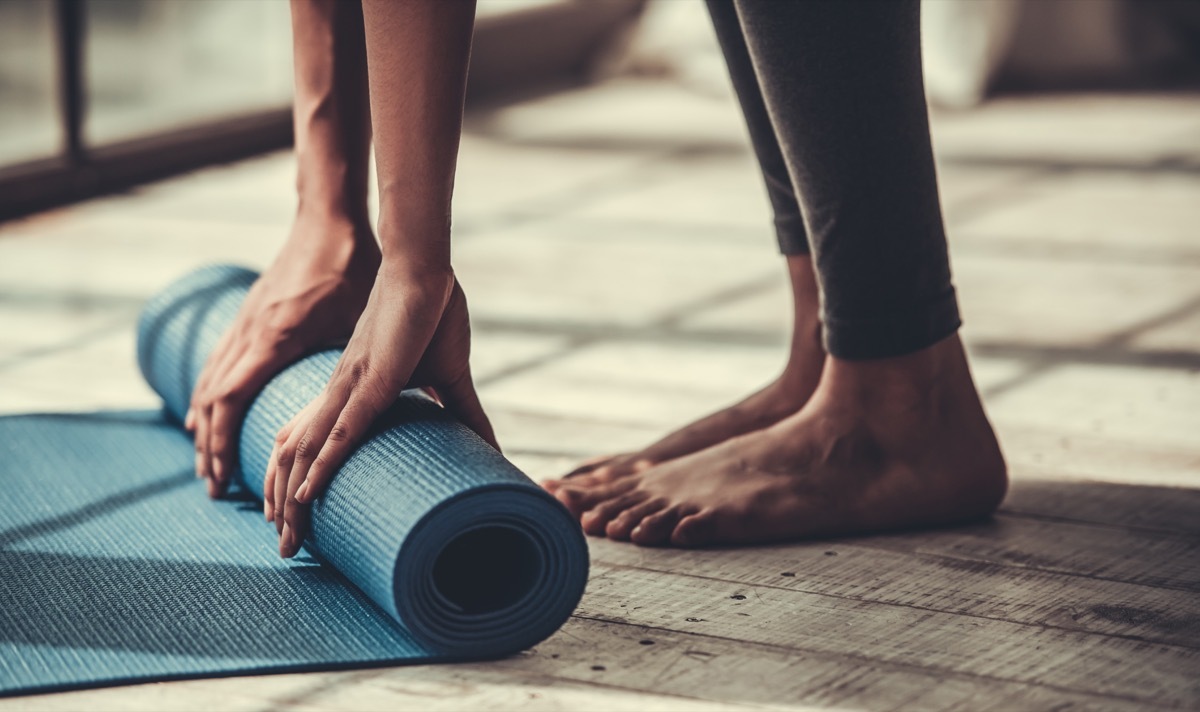 cropped image of woman rolling out exercise mat