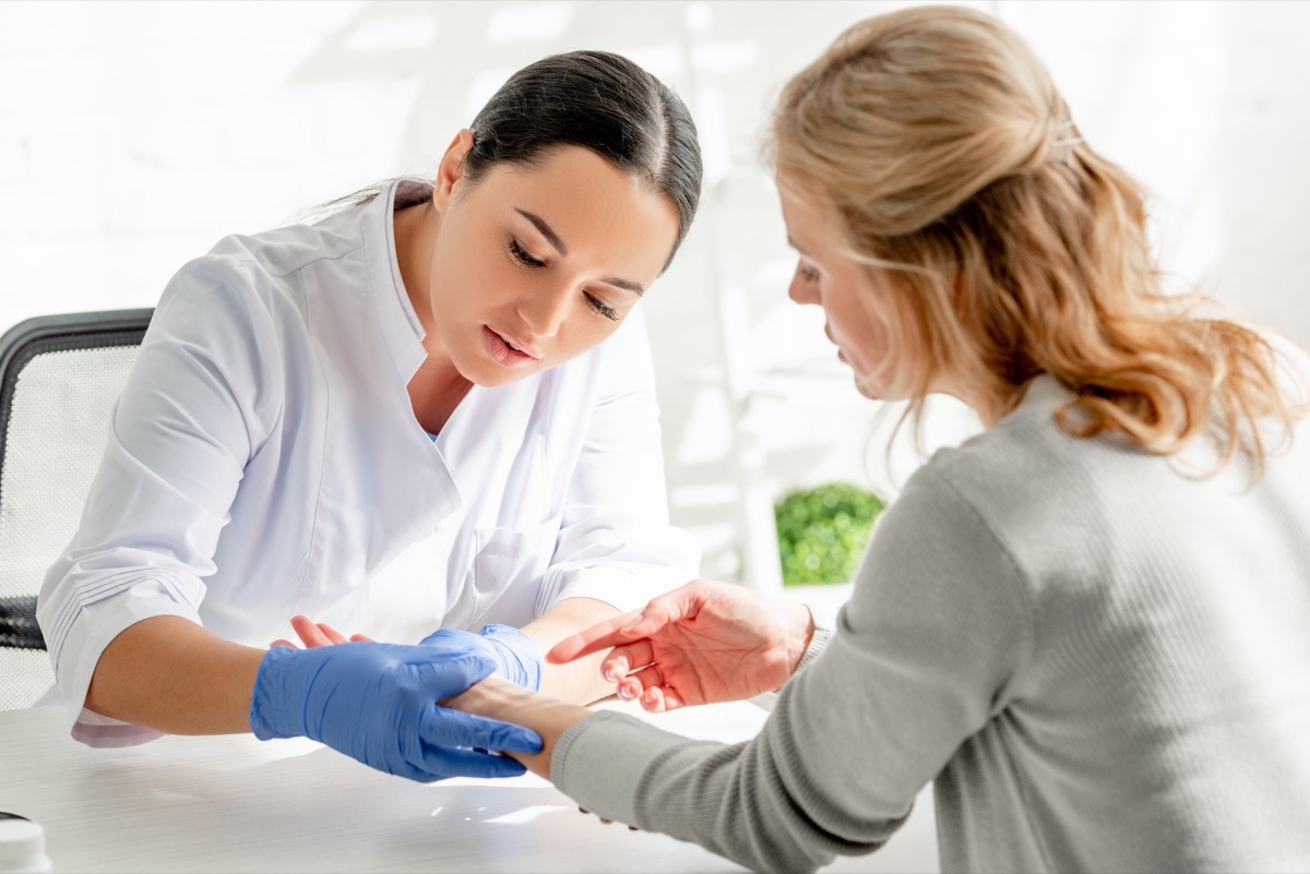 Dermatologist looking at woman's wrist