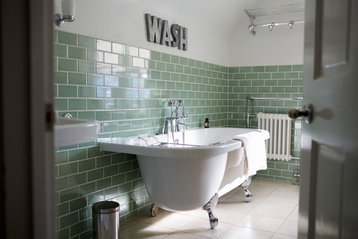 bathroom with freestanding tub and green subway tile, bathroom accessories