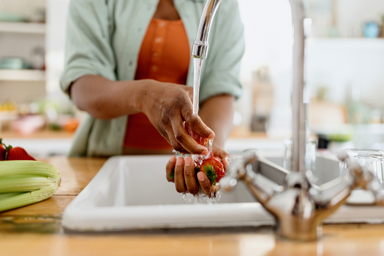 A close up of a person cleaning strawberries in the sink