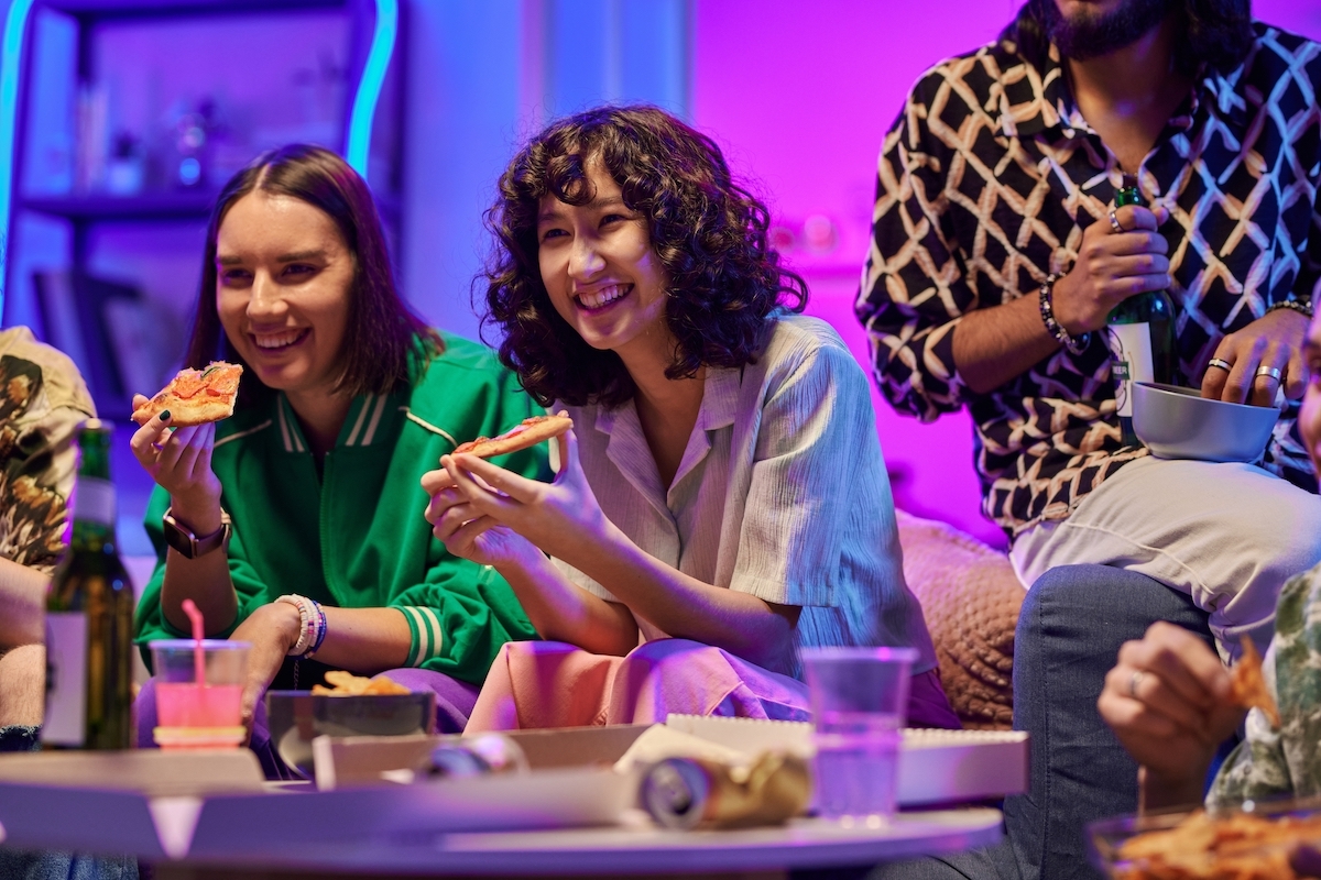 people eating pizza and snacks on a sofa