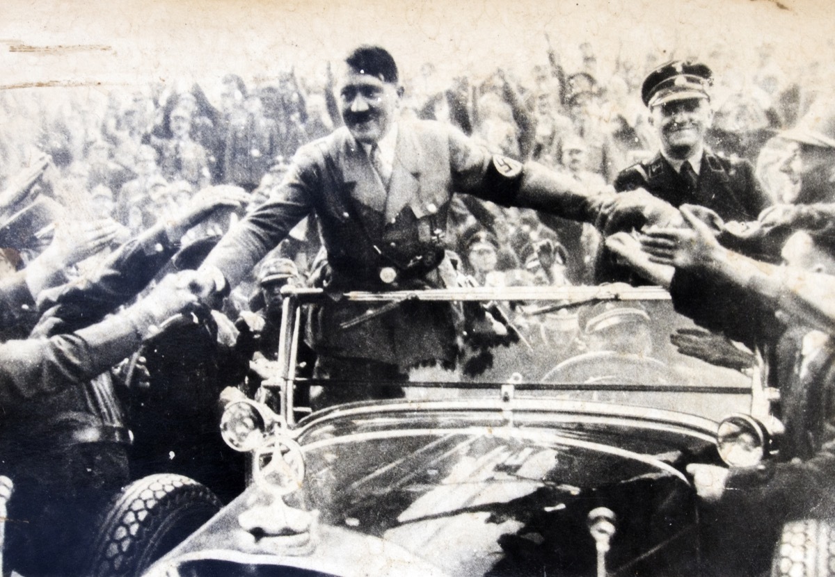 GERMANY - CIRCA 1940s: Adolf Hitler stands in a convertible and shaking hands with his fans, Reproduction of antique photo