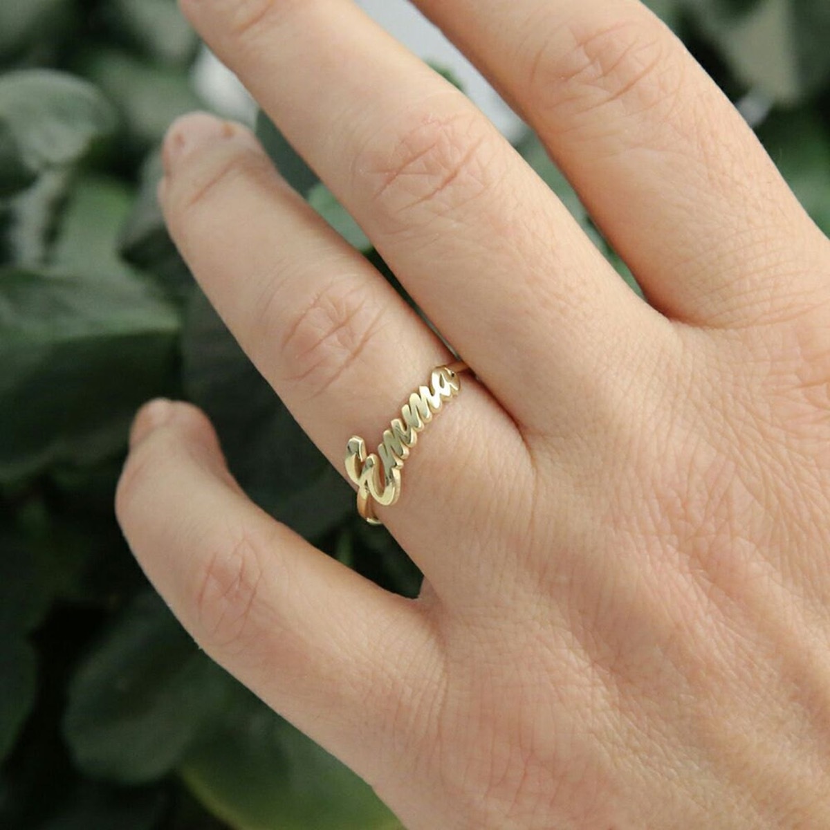 Woman's hans wearing script gold name ring