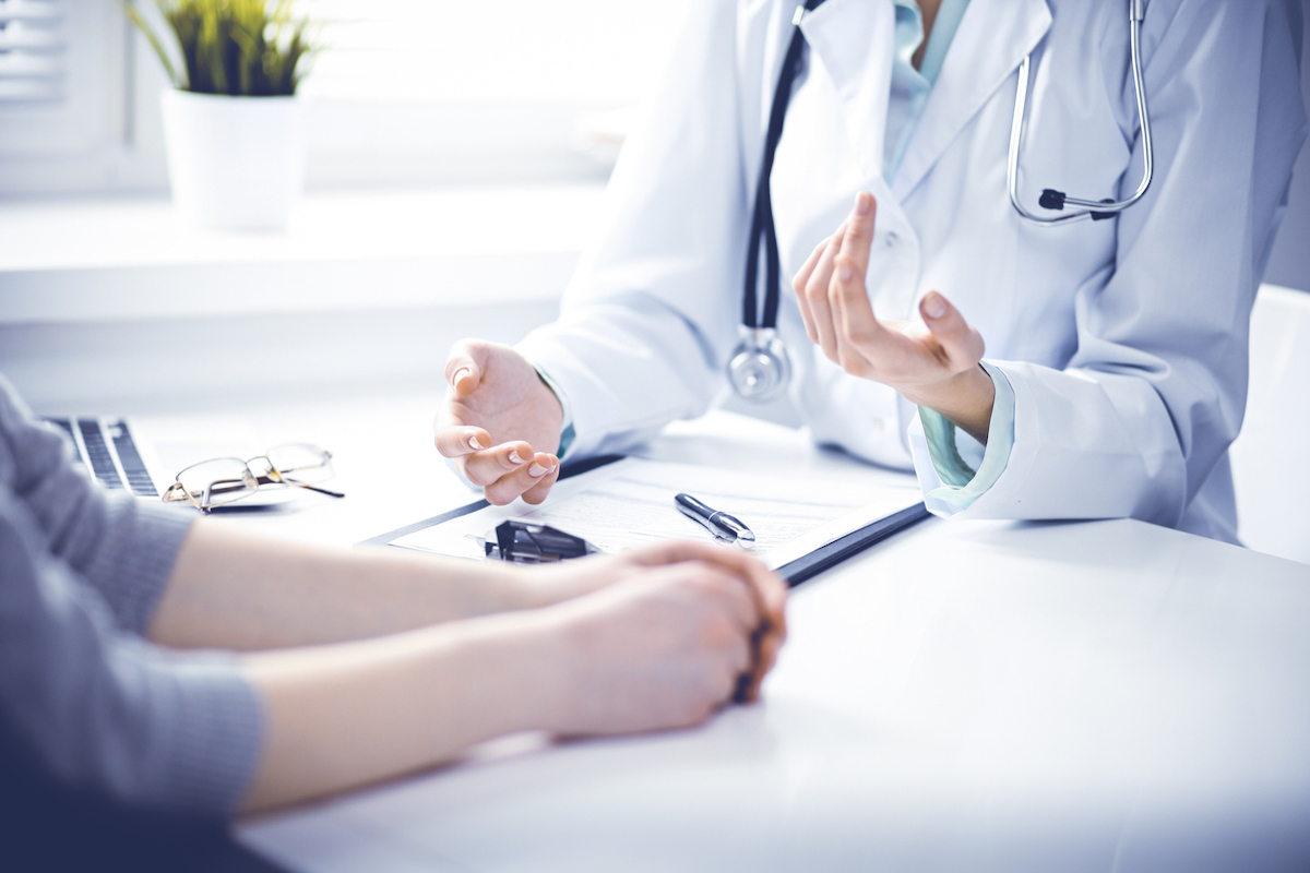 Closeup of woman doctor and woman patient sitting at the desk and talking