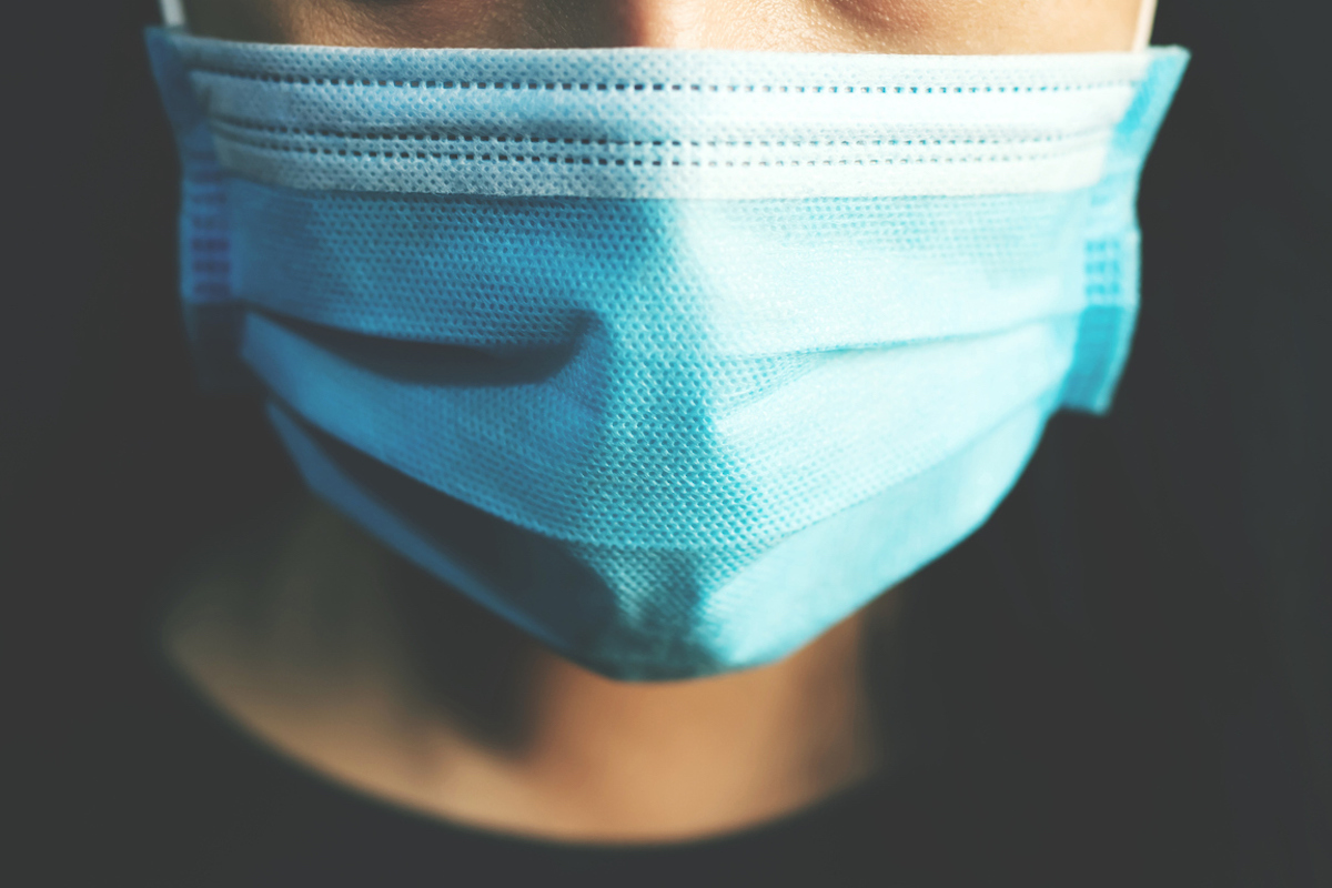 closeup of person wearing blue surgical mask to protect against Covid-19