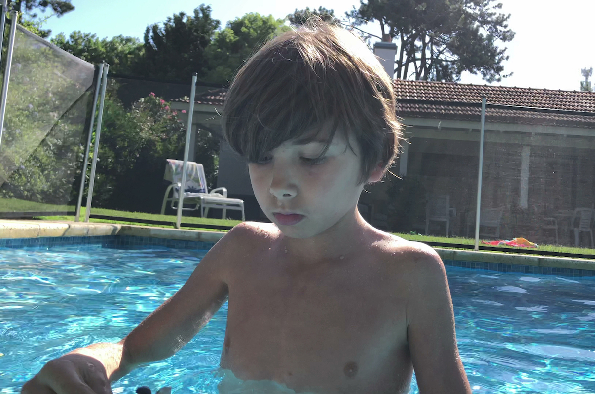 Child playing with toys inside swimming pool as storm starts