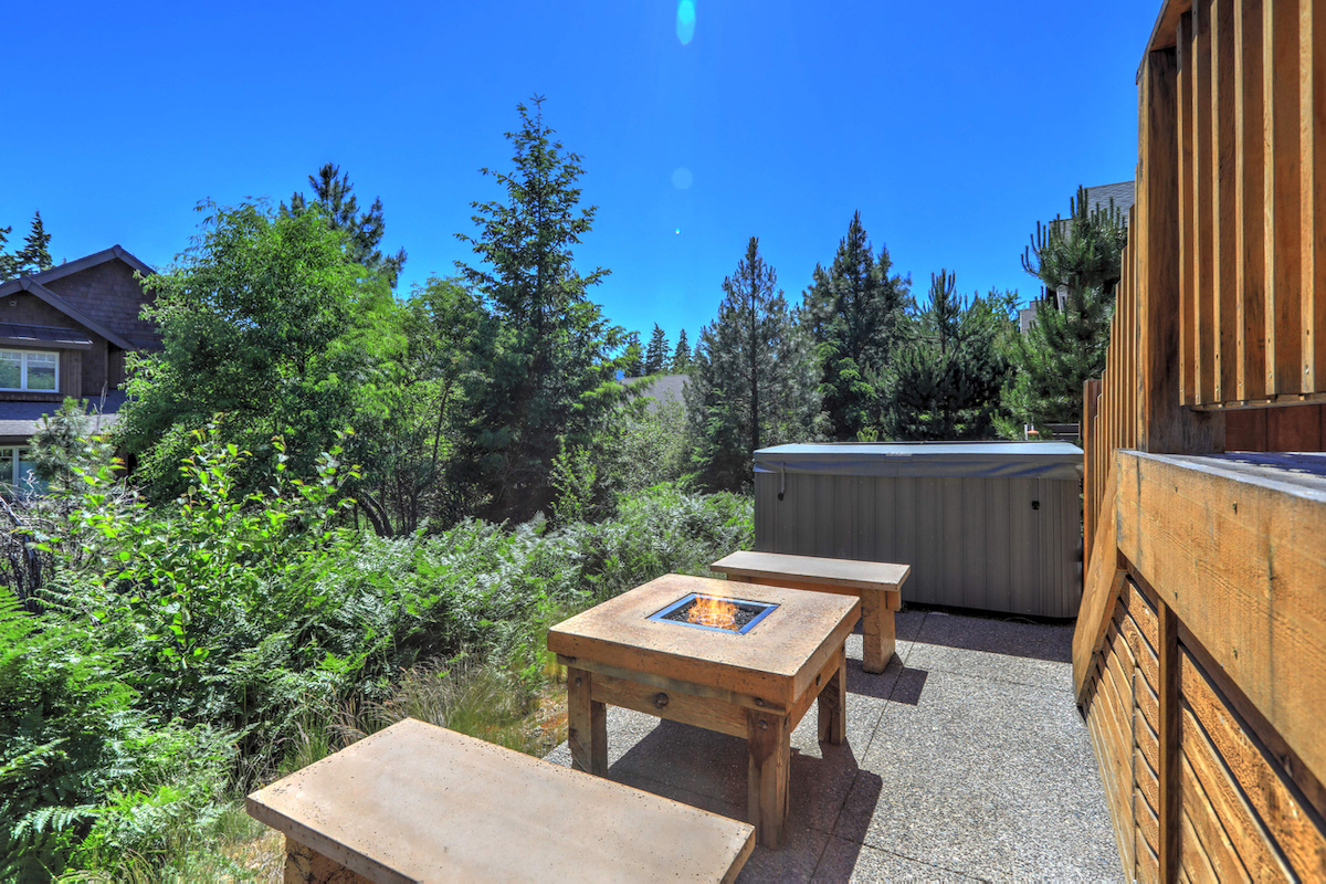 Small but open to greenery back yard space with fire pit table and hot tub and wooden deck