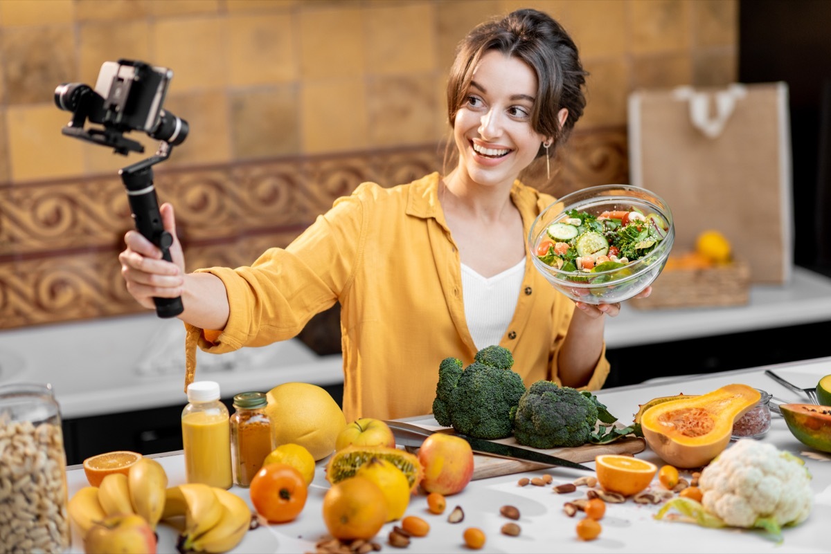 Young and cheerful woman vlogging on mobile phone about healthy food and cooking. Concept of healthy eating and social media influencing