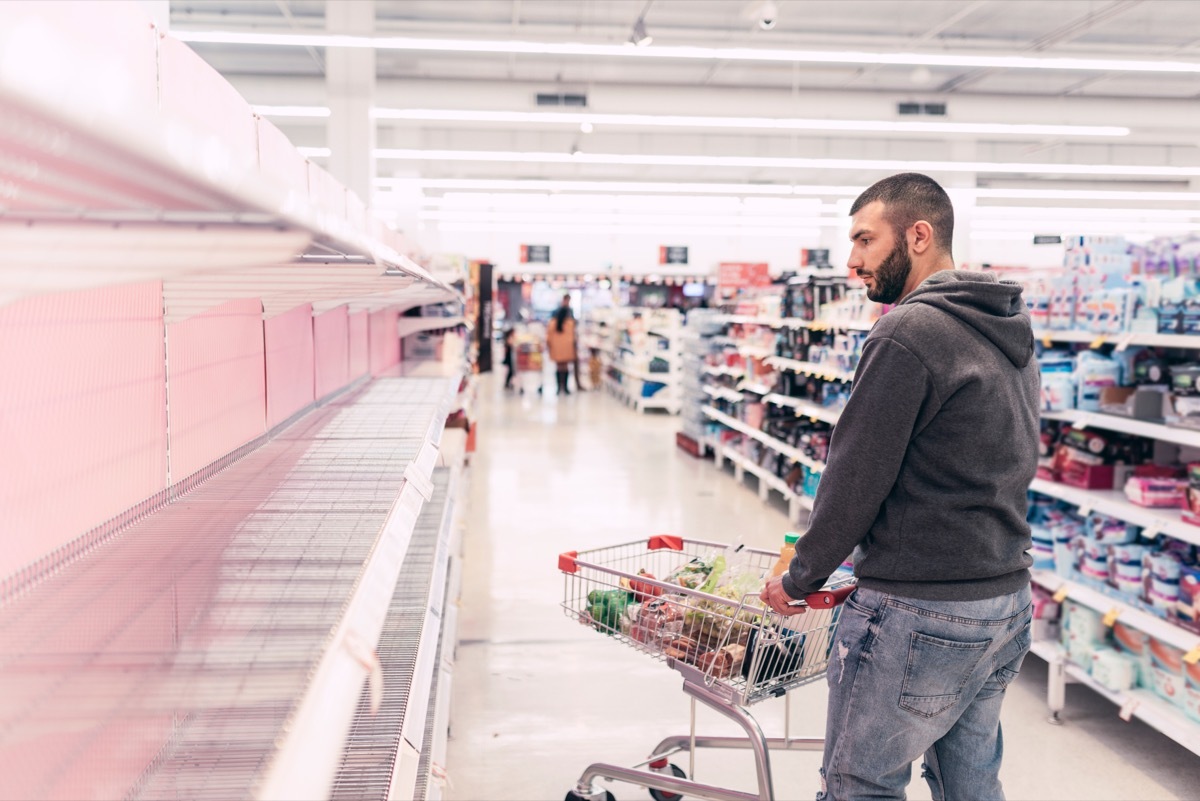 man looking at empty shelves