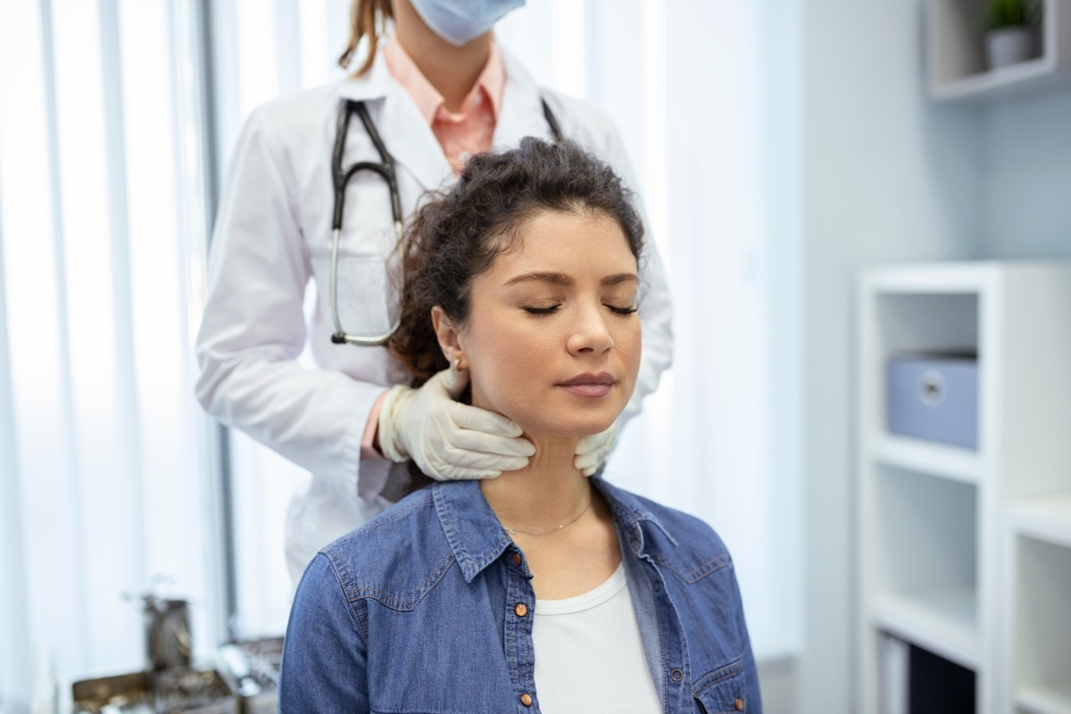 Endocrinologist examining throat of young woman in clinic