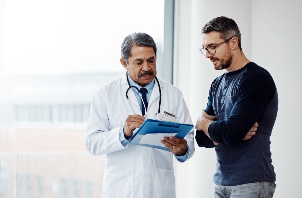 man asking his doctor questions when looking at medical papers