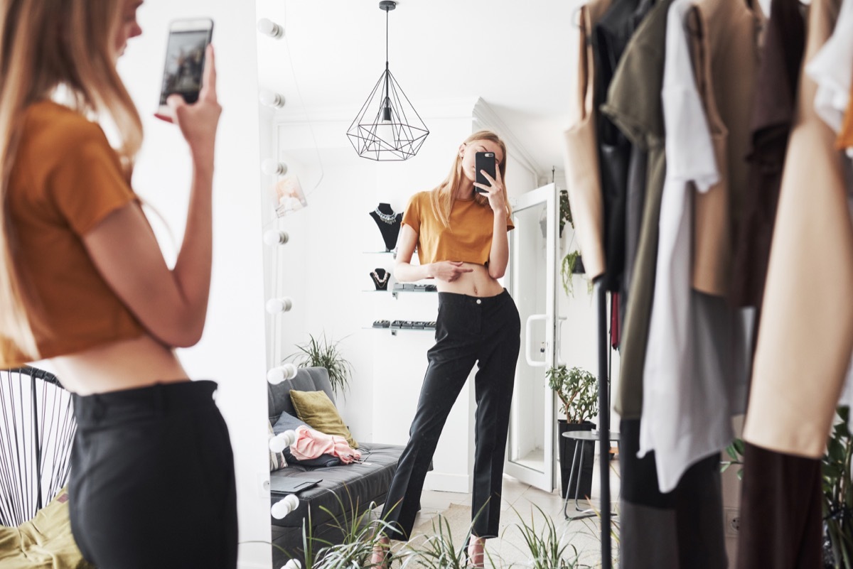 female influencer taking a photo of her outfit in a full length mirror