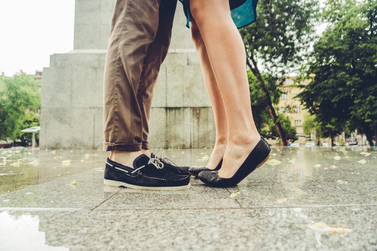 feet of woman on tiptoes to kiss man