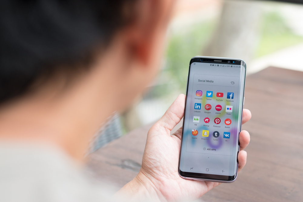 An over-the-shoulder view of someone looking at their Android phone with apps on the screen