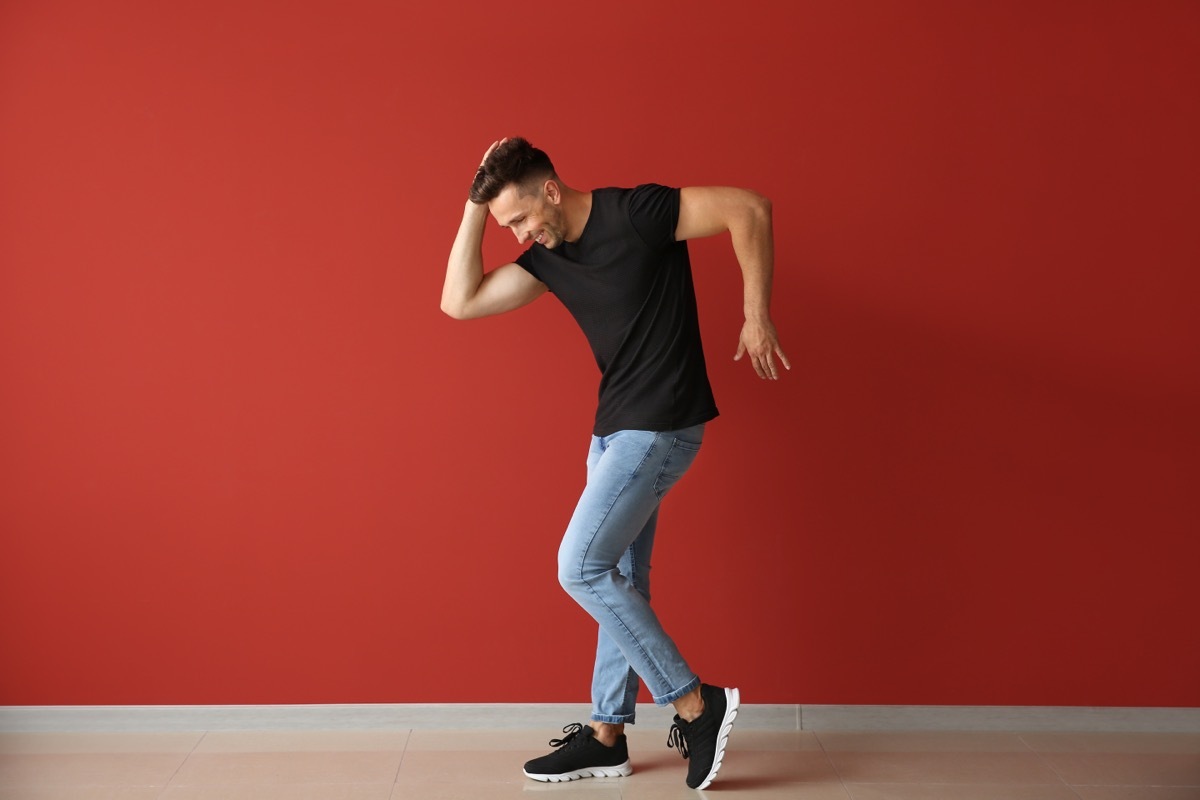 Handsome young man dancing against color wall