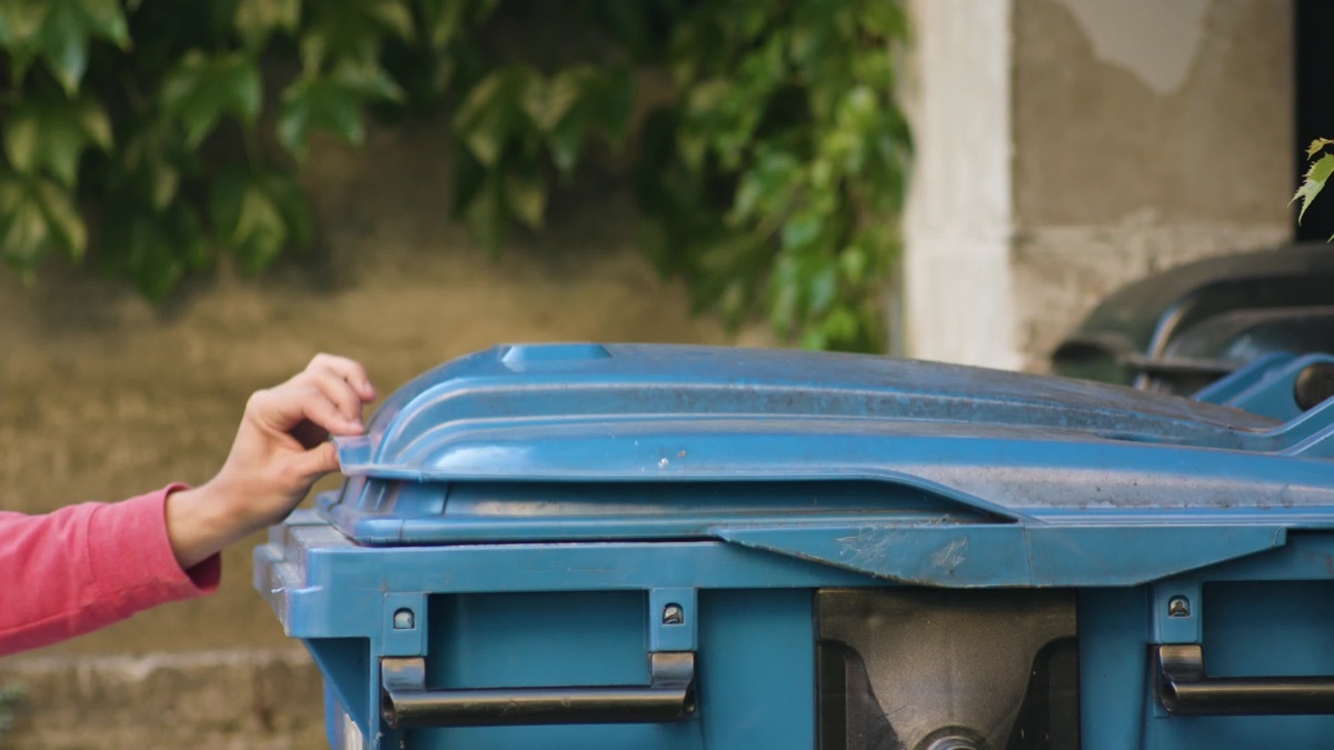 Young man in red sportswear throwing away rubbish. Close-up shot