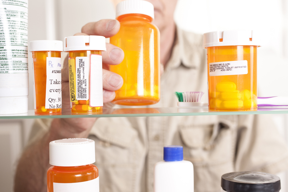 Senior adult man gets prescription medicines out of his medicine cabinet