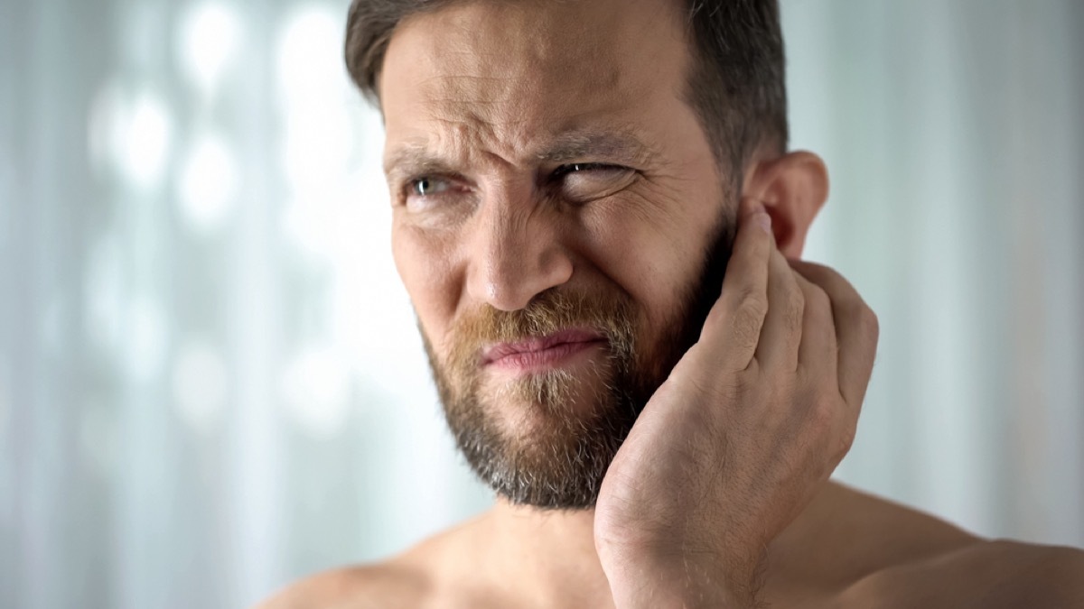 white man pressing his ear and looking concerned