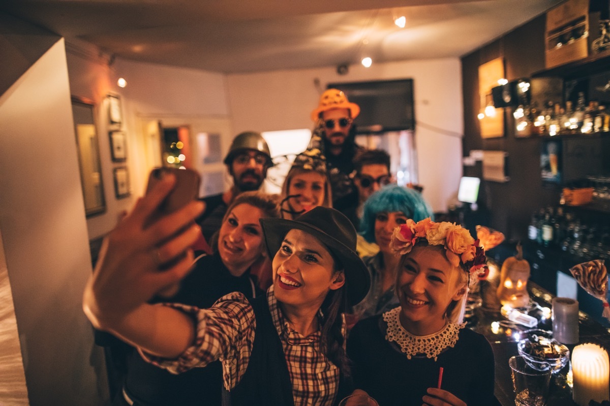 Group of costumed people having fun and making selfies on Halloween party