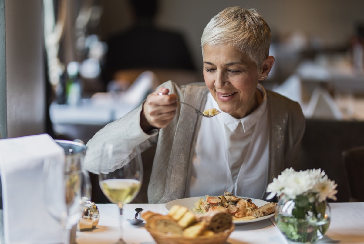 woman sitting with hand in her lap eating dinner