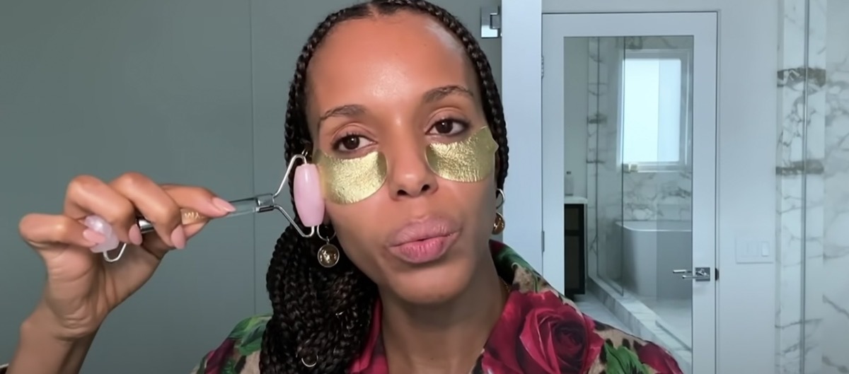 kerry washington wearing gold undereye patches and using a jade roller with her hair in a braid