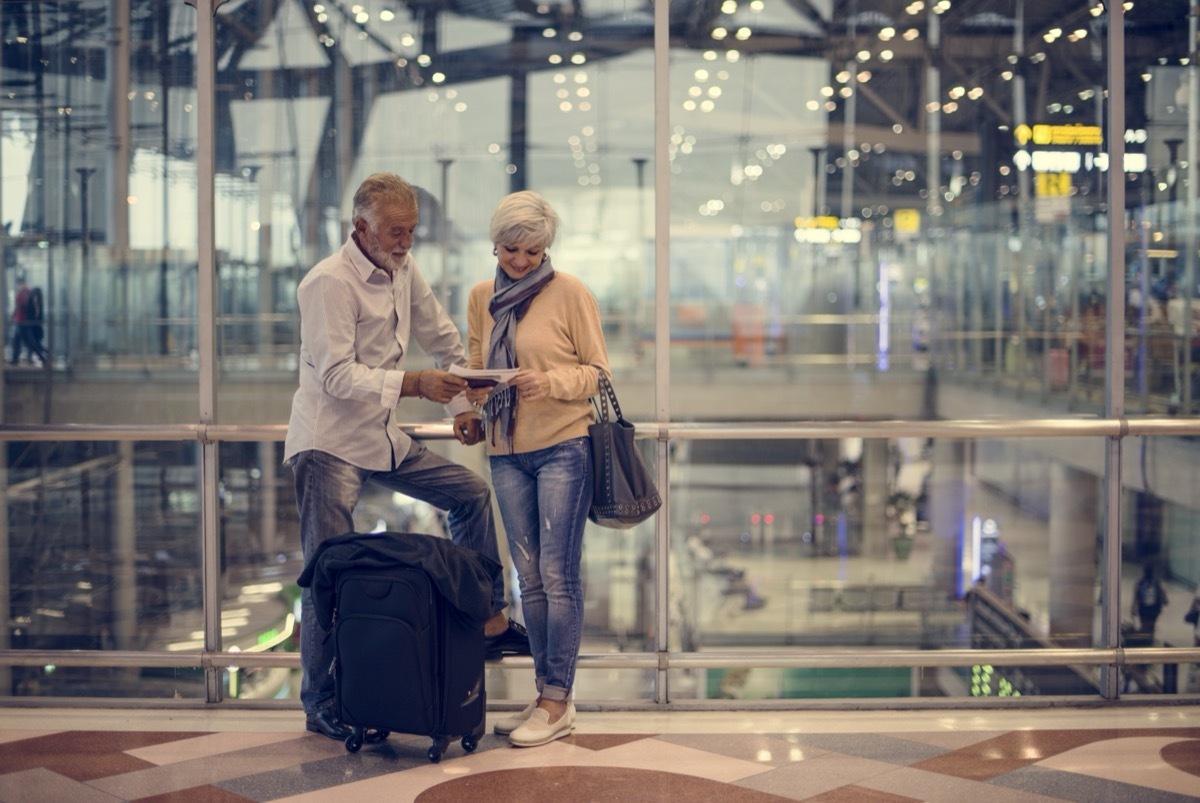 An elderly couple excitedly look at their travel agenda or passports.