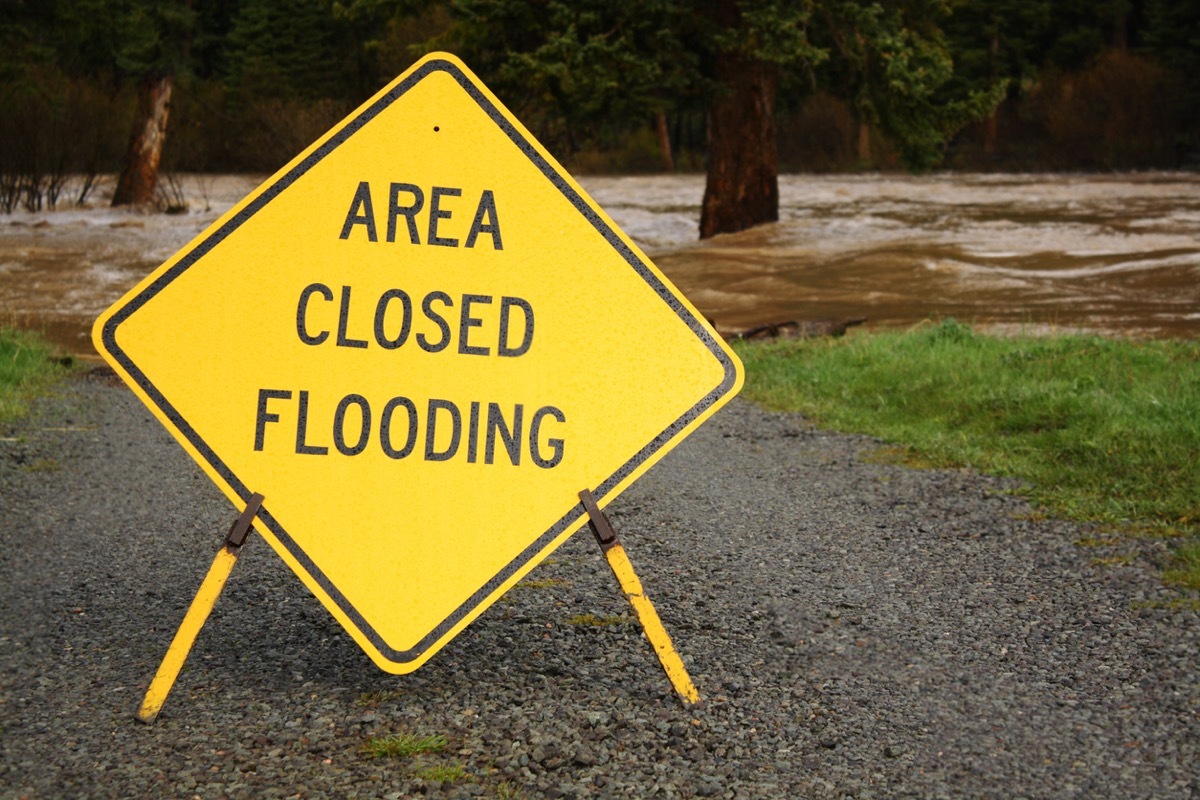 Flooding river and road closed sign.