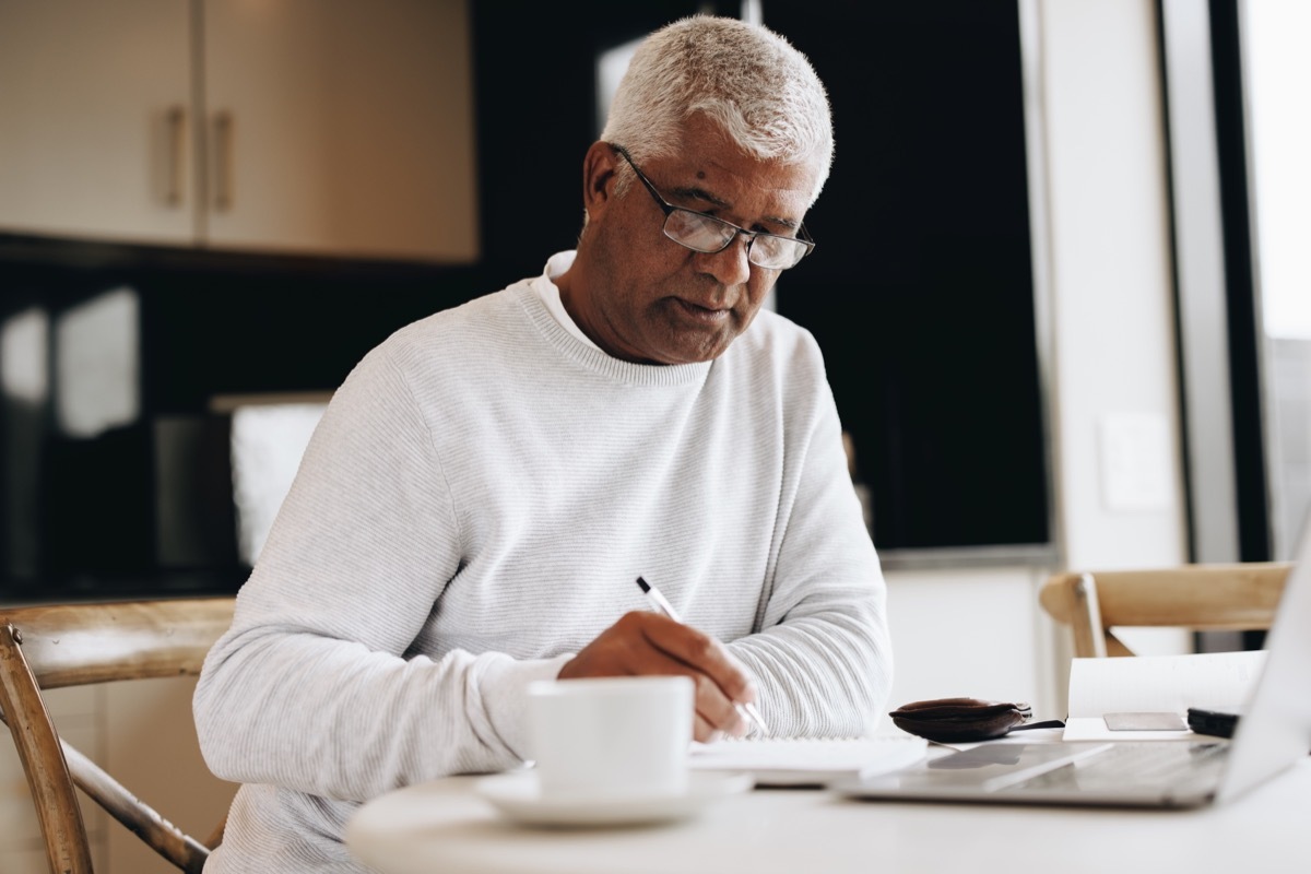 white haired man journaling