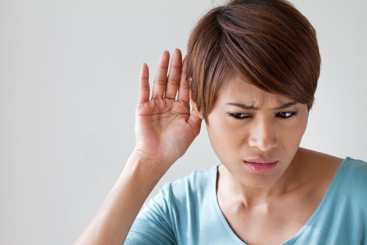 Woman Holding Hand Up to Ear