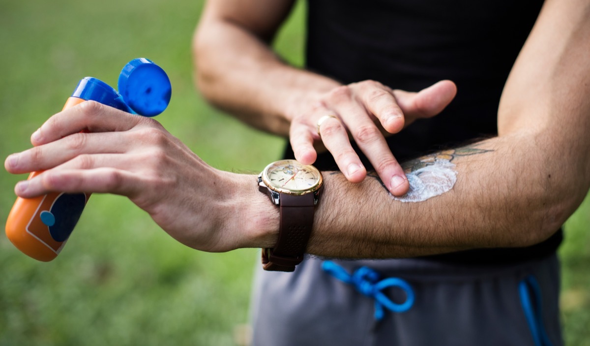 Man putting sunscreen on a tattoo on his arm