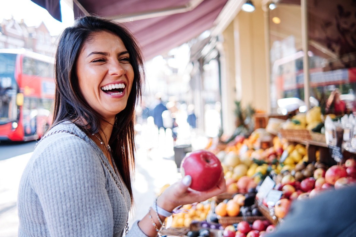 Smiling woman picking out an apple at the farmer's market