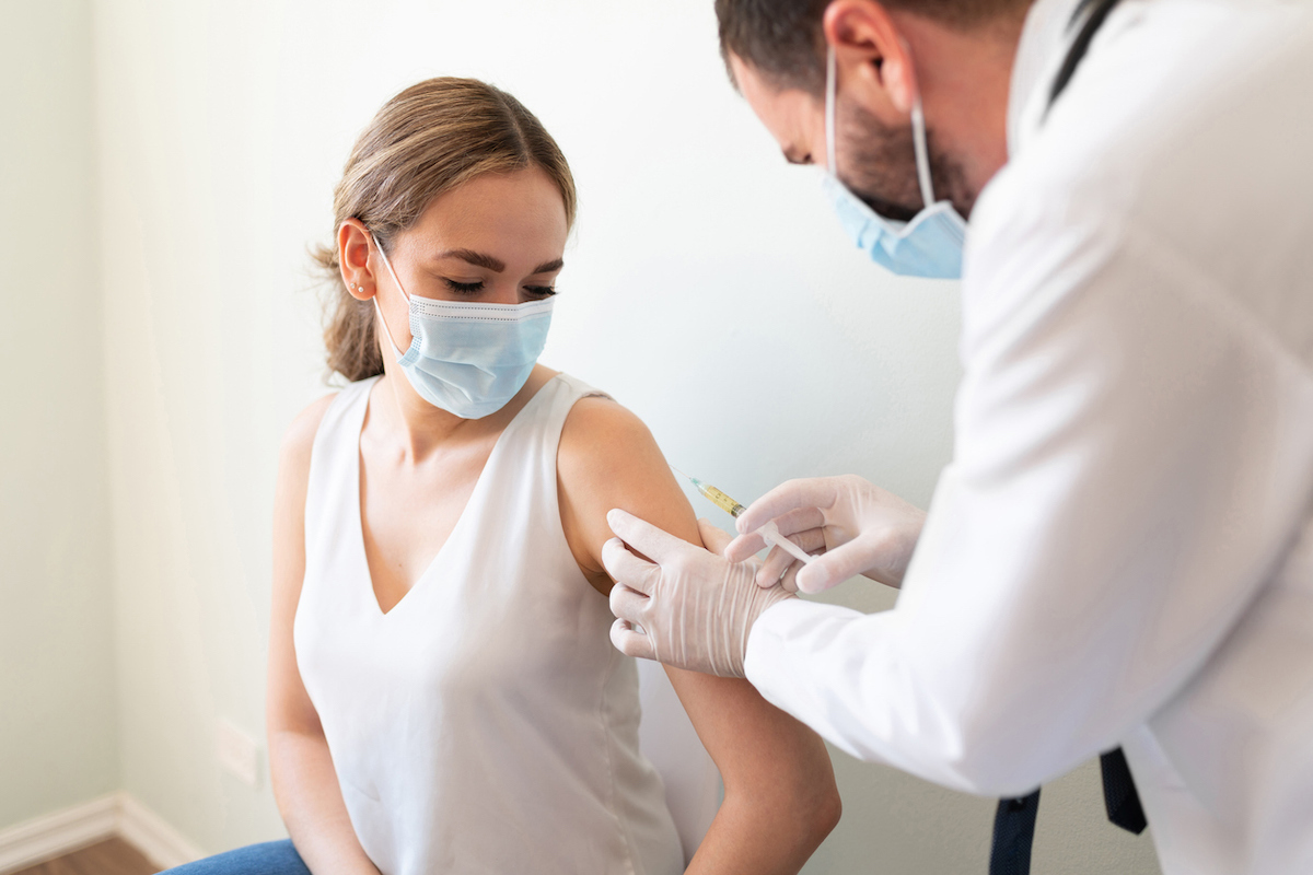 Closeup of a nervous woman and her doctor wearing face masks and getting the COVID vaccine