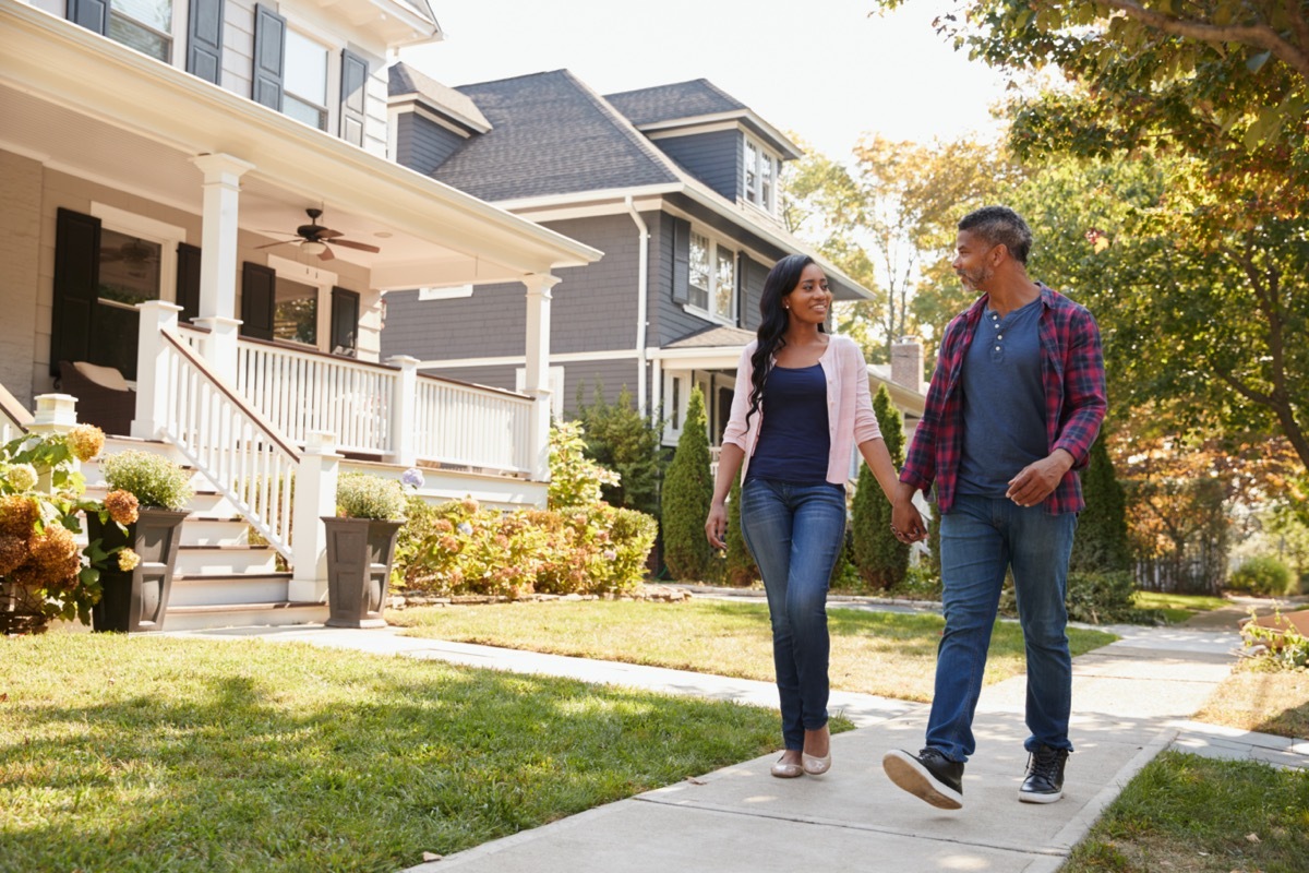 Couple Walking Along Suburban Street Holding Hands