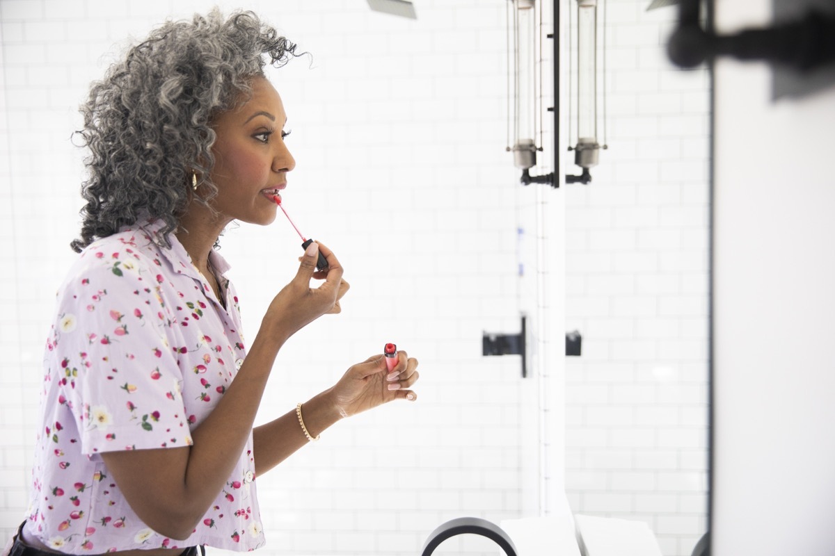 A beautiful woman puts on her makeup in a bathroom