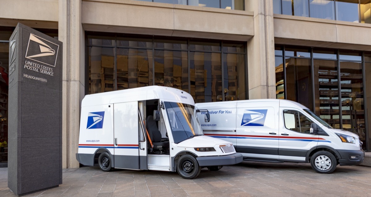 A pair of Next Generation Delivery Vehicle mail trucks at a USPS station