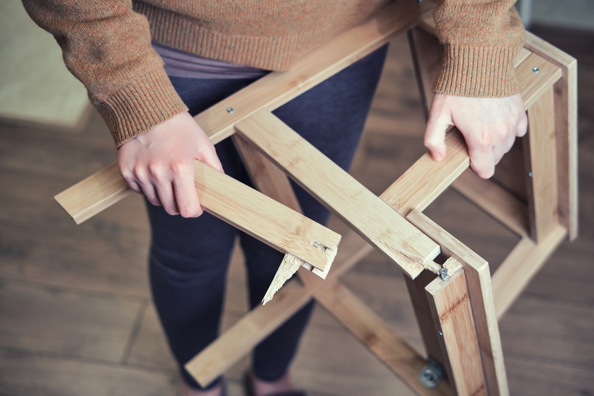 person holding broken chair legs