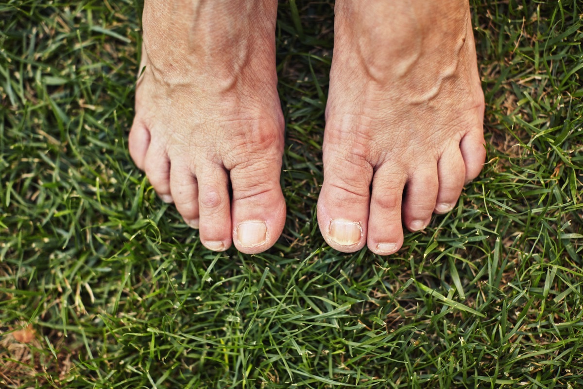 Barefoot senior standing on the green grass