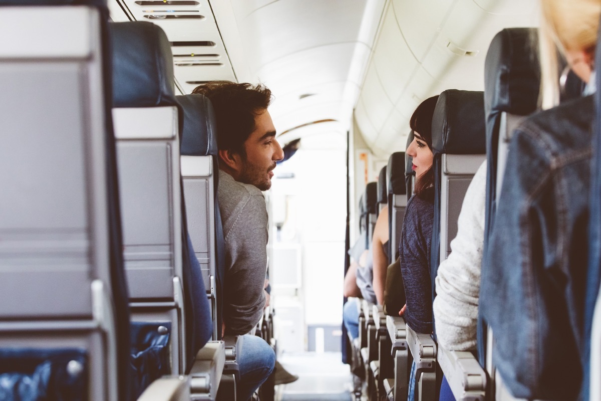 Interior of airplane with people sitting on seats and talking. Friends traveling by flight.