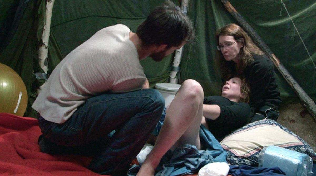 Born in the Wild Scene in a tent in the woods where a woman gives birth.