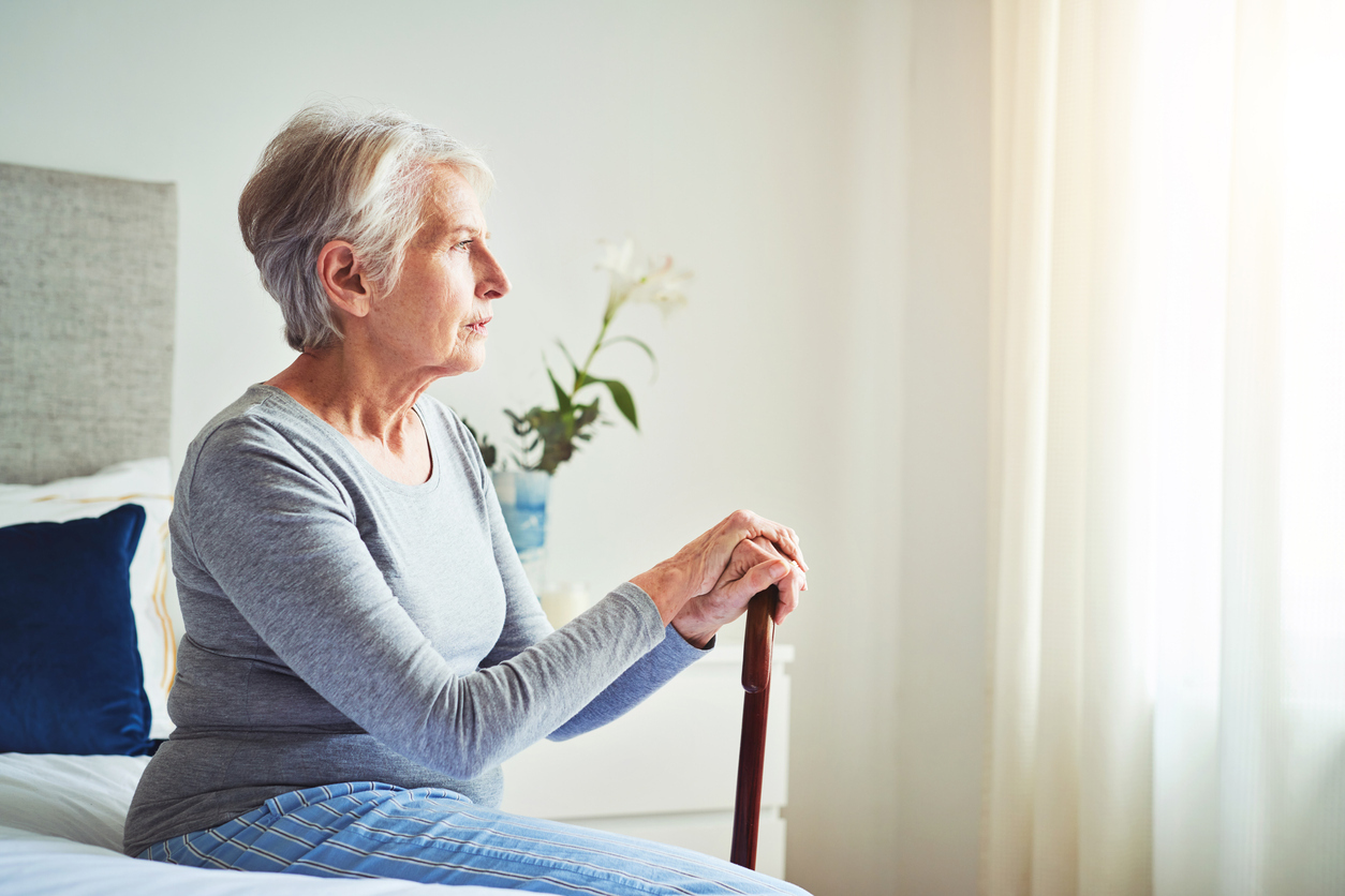 Senior woman sitting on a bed.