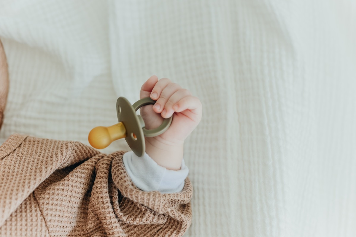 close up on baby's fist holding a pacifier