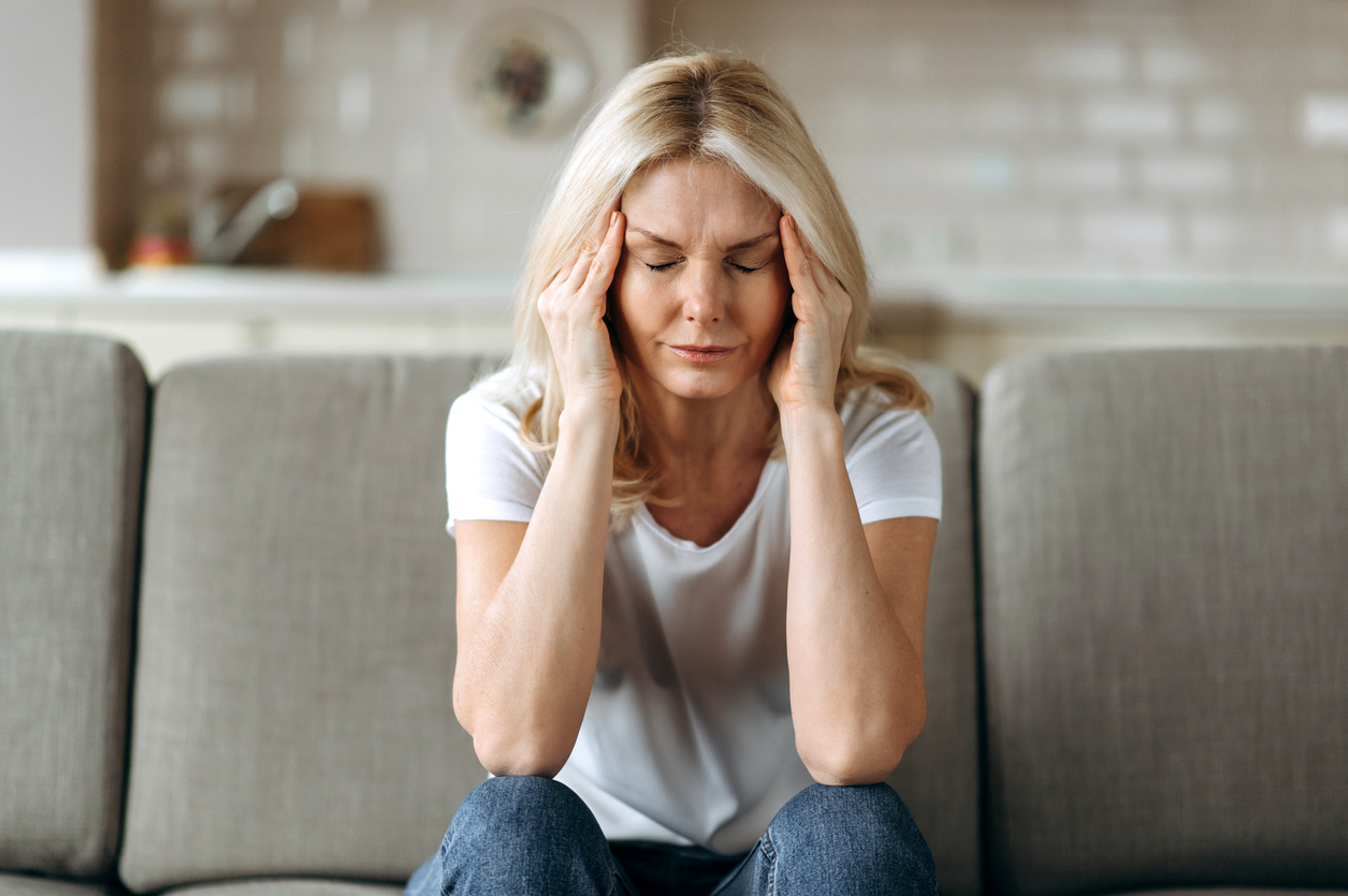 Woman sitting on couch with a headache.