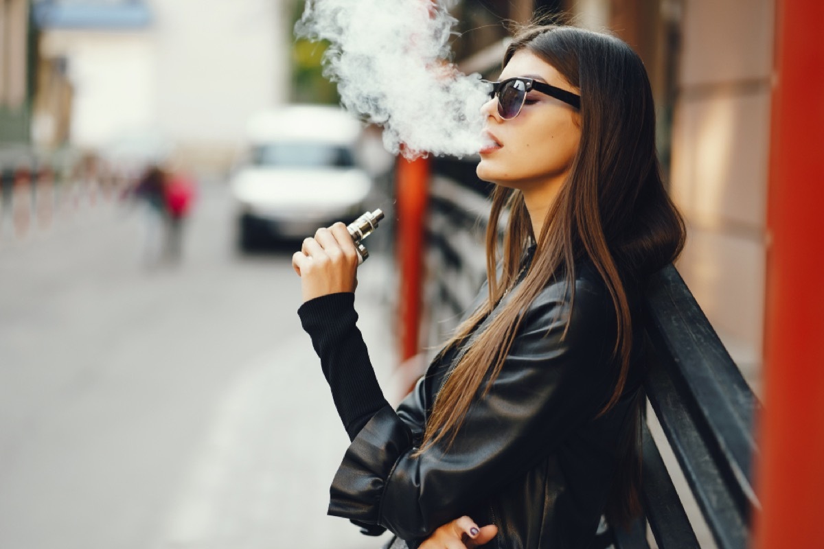 young white woman smoking an e-cigarette outside