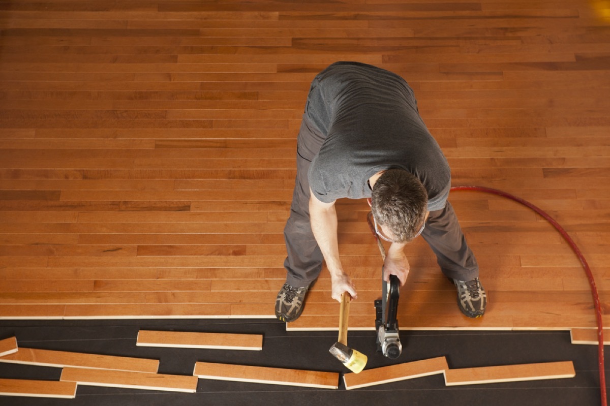 man in gray shirt and pants installing hardwood floor