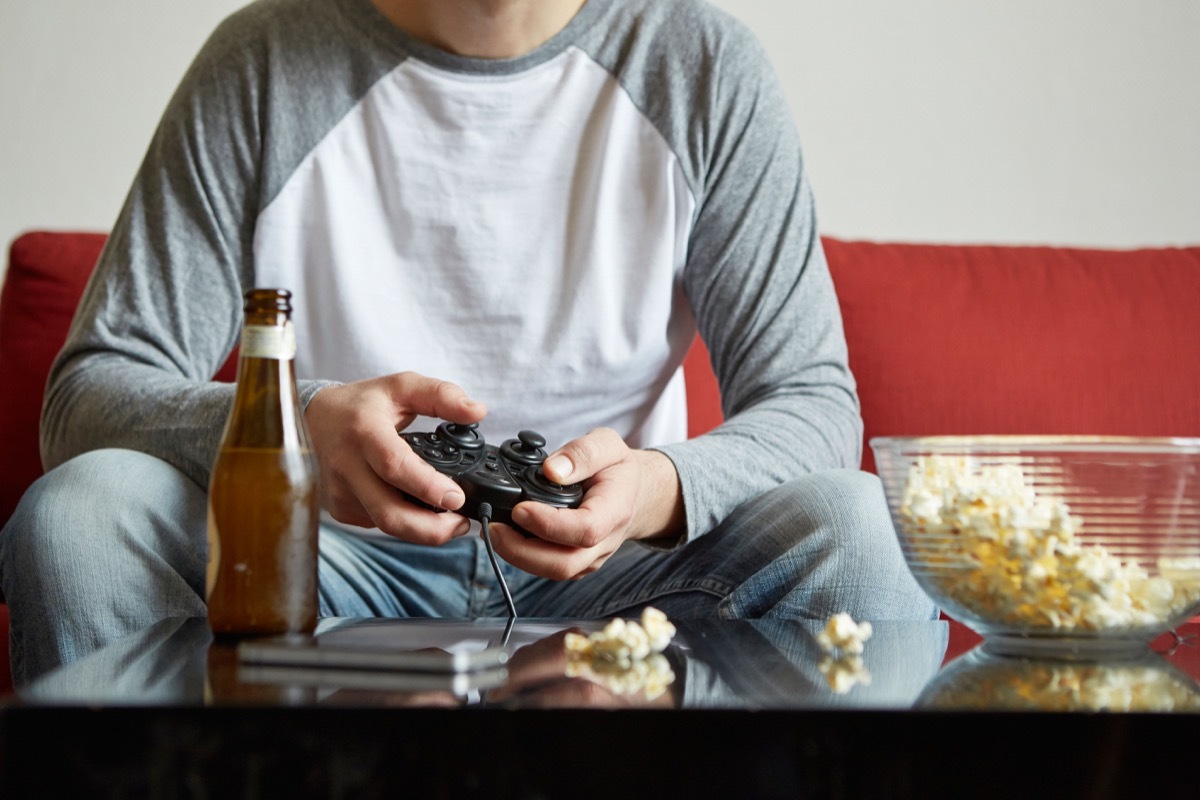 Man playing video games on the sofa after calling in sick to work