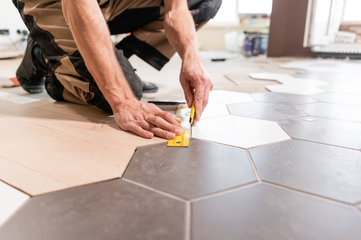 Professional man installing tile on the floor