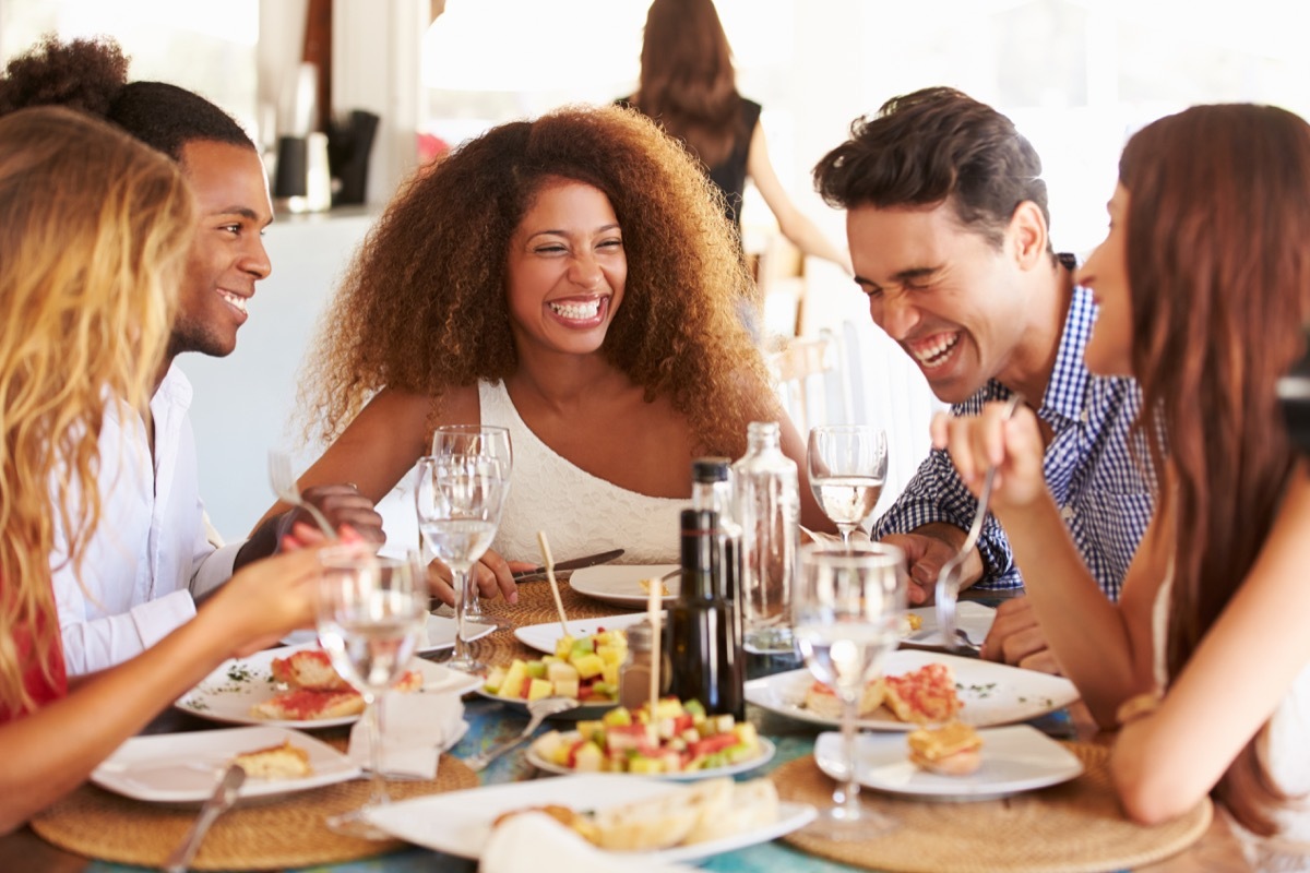 Group of multicultural friends laughing and enjoying a meal