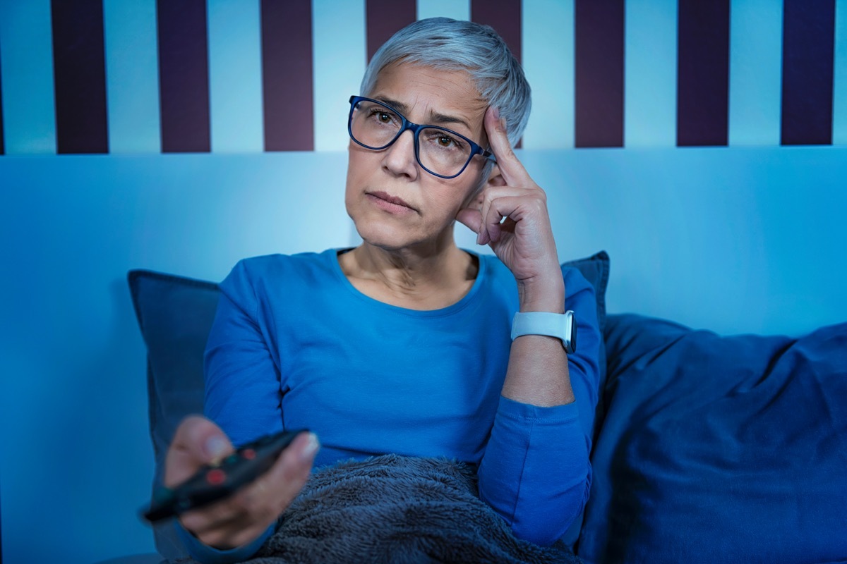 Senior woman in bed, watching TV late at night.