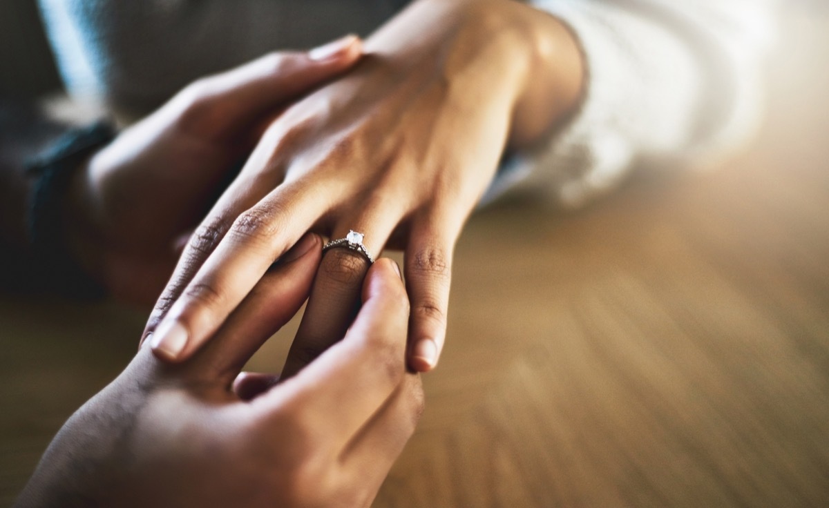 man putting engagement ring on woman's hand