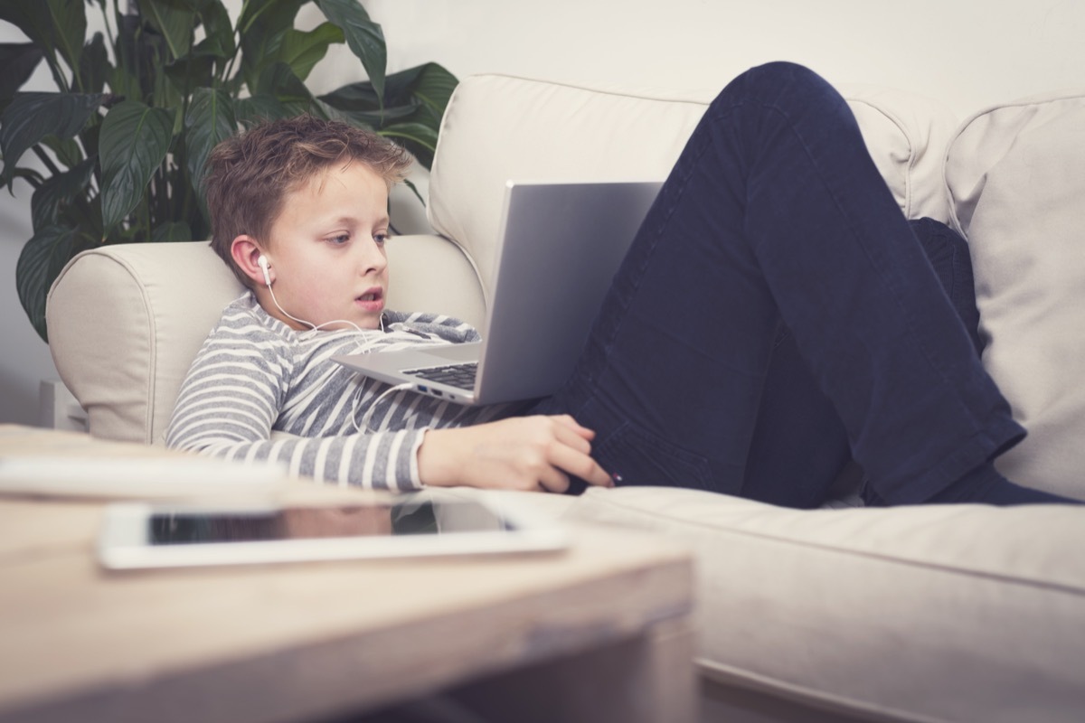 young white boy using laptop on couch